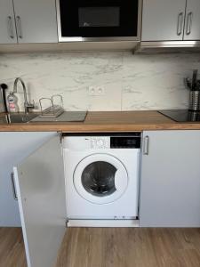 een keuken met een wasmachine en een wastafel bij Studio Saint Cyr in Saint-Cyr-lʼÉcole