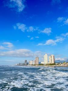 uma vista para a praia a partir da água com edifícios em Suíte Garden na Praia Grande