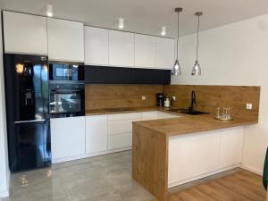 a kitchen with white cabinets and a black refrigerator at ApartamentAugust in Zielona Góra