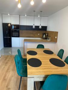 a kitchen with a wooden table and green chairs at ApartamentAugust in Zielona Góra