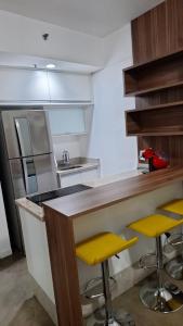 uma cozinha com um balcão e dois bancos amarelos em FLAT HOTEL EM ALPHAVILLe ÓTIMA LOCALIZAÇÃO em Barueri