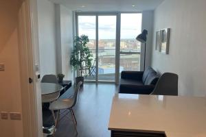 uma sala de estar com um sofá e uma mesa com cadeiras em Cozy Living with Balcony View em Croydon