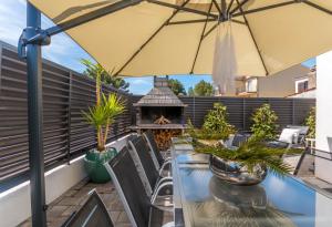 a patio with a table with an umbrella and a fireplace at House with pool Ledenko in Biograd na Moru