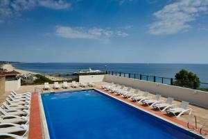 a swimming pool with lounge chairs and the ocean at Bournemouth Highcliff Marriott Hotel in Bournemouth