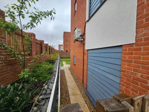 a retaining wall next to a building with a blue garage at Modern 3 Bedroom Town House in Ipswich