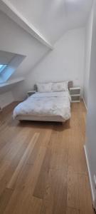 1 dormitorio blanco con 1 cama y suelo de madera en Appartement pré de Paris, en Gagny