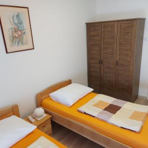 een slaapkamer met 2 aparte bedden en een kast bij Apartmani Slavulj in Fažana