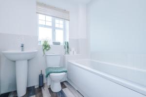 uma casa de banho branca com um lavatório, uma banheira e um WC. em Modern Semi detached in a quiet location, Driveway parking em Ewloe