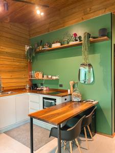 eine Küche mit einem Tisch und einer grünen Wand in der Unterkunft Cabana equipada em meio à natureza em Pomerode in Pomerode