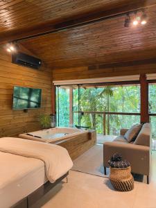 1 dormitorio con bañera, cama y sofá en Cabana equipada em meio à natureza em Pomerode, en Pomerode