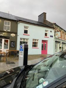 a car parked in front of a building with a parking meter at Pink door house in Clifden in Clifden
