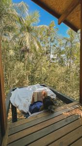 a man laying on a bed reading a book at Cabana equipada em meio à natureza em Pomerode in Pomerode