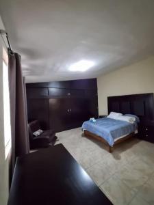 ein Schlafzimmer mit einem Bett und einem Stuhl in der Unterkunft Amplia Casa en Sector Viñedos (factura) in Torreón