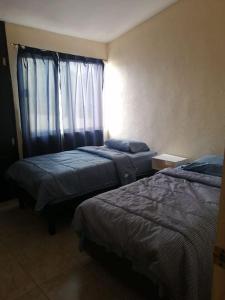 a hotel room with two beds and a window at Amplia Casa en Sector Viñedos (factura) in Torreón