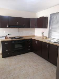 a kitchen with brown cabinets and a stove top oven at Amplia Casa en Sector Viñedos (factura) in Torreón