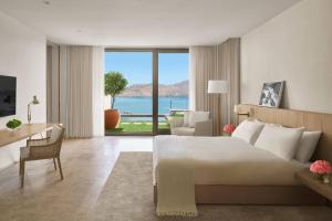a bedroom with a bed and a desk and a large window at The Bodrum EDITION in Yalıkavak