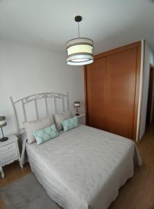 a bedroom with a white bed with a wooden door at APARTAMENTO A CHILENA in Cambados