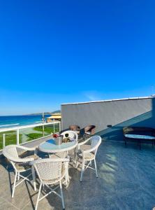 a patio with a table and chairs and the beach at Central Praias III in Cabo Frio
