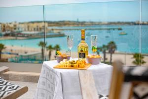 a table with a bottle of wine and cheese and wine glasses at Birzebbuga -Two Bed Penthouse in Birżebbuġa