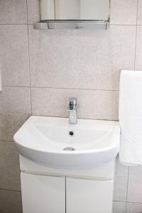 La salle de bains est pourvue d'un lavabo blanc et d'un miroir. dans l'établissement Birzebbuga -Two Bed Penthouse, à Birżebbuġa
