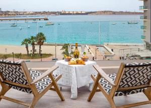 a table with two chairs and a view of the ocean at Birzebbuga -Two Bed Penthouse in Birżebbuġa