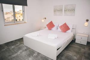 ein weißes Schlafzimmer mit einem weißen Bett und orangefarbenen Kissen in der Unterkunft Birzebbuga -Two Bed Penthouse in Birżebbuġa