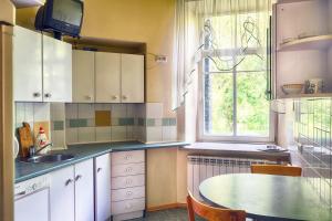een keuken met een tafel, een wastafel en een raam bij Private rooms with balcony next to station in Vilnius