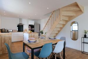 a kitchen and dining room with a wooden table and blue chairs at Maison proche gare de Guingamp in Ploumagoar