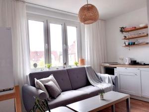 salon z kanapą i oknami w obiekcie Apartament Plaża Zachodnia - 400 m do morza w Kołobrzegu