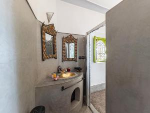 La salle de bains est pourvue d'un lavabo et de 2 miroirs sur le mur. dans l'établissement Riad Minorisa, à Marrakech