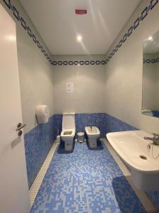 a blue and white bathroom with a toilet and a sink at Apartment with Breathtaking view in Praia da Areia Branca
