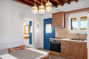 a kitchen with a table and a blue door at Pigados Beach House Kimolos in Kimolos