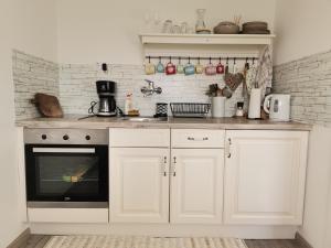 a kitchen with white cabinets and a stove top oven at Počitniška hiša Pavlek in Ivanjkovci