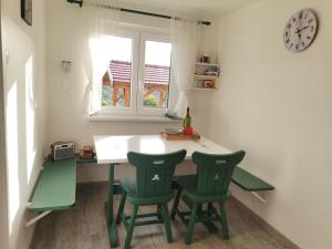 une cuisine avec une table et deux chaises vertes dans l'établissement Počitniška hiša Pavlek, à Ivanjkovci
