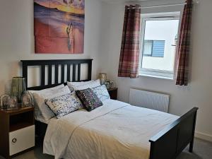 ein Schlafzimmer mit einem Bett mit Kissen und einem Fenster in der Unterkunft Modern 3 Bedroom Town House in Ipswich in Ipswich