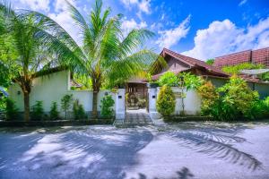 dom z palmami przed nim w obiekcie Asoka Bungalows w mieście Nusa Penida
