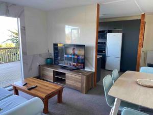 a living room with a tv and a table and a kitchen at 3 bed apartment with stunning harbour views in Lower Hutt