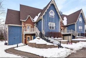 une grande maison bleue avec de la neige au sol dans l'établissement Cosy Chalet - 4 Season Family Oasis, à Collingwood