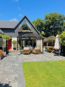 a patio with tables and an umbrella in front of a house at Stunning cottage in Christchurch