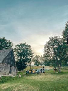 een groep mensen die in een veld naast een schuur zitten bij Highlander villas in Žabljak