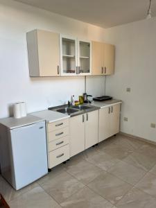 La cuisine est équipée de placards blancs, d'un évier et d'un réfrigérateur. dans l'établissement Regatta Inn, à Ulcinj