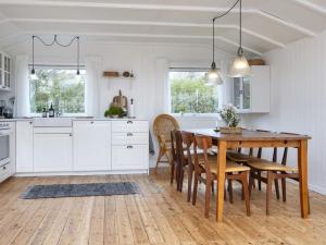 a white kitchen with a wooden table and chairs at Holiday home Struer XI in Struer