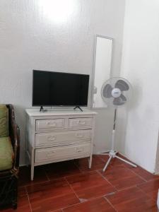 uma televisão numa cómoda num quarto com uma ventoinha em La casa 19 em Cancún