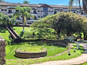 a garden with a pond in front of a building at Flat encantador localizado no melhor de Serra Negra - SP in Serra Negra