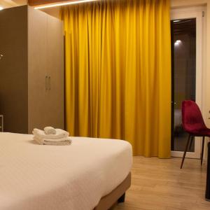 ein Schlafzimmer mit einem Bett und einem gelben Vorhang in der Unterkunft KRINÒ hotel in Augusta