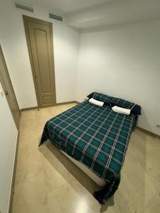 um quarto com uma cama com um cobertor xadrez em Hotelly Atocha em Madri