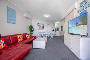 uma sala de estar com um sofá vermelho e uma televisão de ecrã plano em Absolute Beachfront Penthouse - Ramada Marcoola em Marcoola