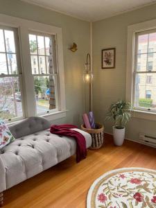 uma sala de estar com um sofá e duas janelas em Historic Downtown Riverview Flat, No 3 em Astoria