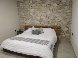 a bed in a room with a stone wall at Casa Xahá in Tecozautla