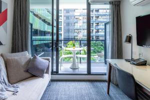 una camera d'albergo con divano, scrivania e finestra di Corporate Living Accommodation Abbotsford a Melbourne